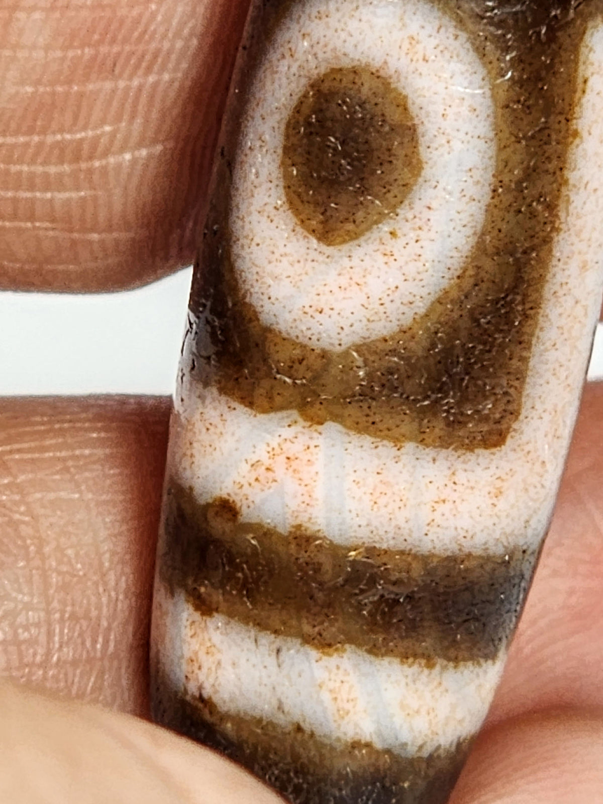 Antique two eye dzi At-092724-2EBS, Face B, second closed eye centred on dark brown agate with rose-peach tinted cream motif lines from extreme cinnabar saturation, unretouched