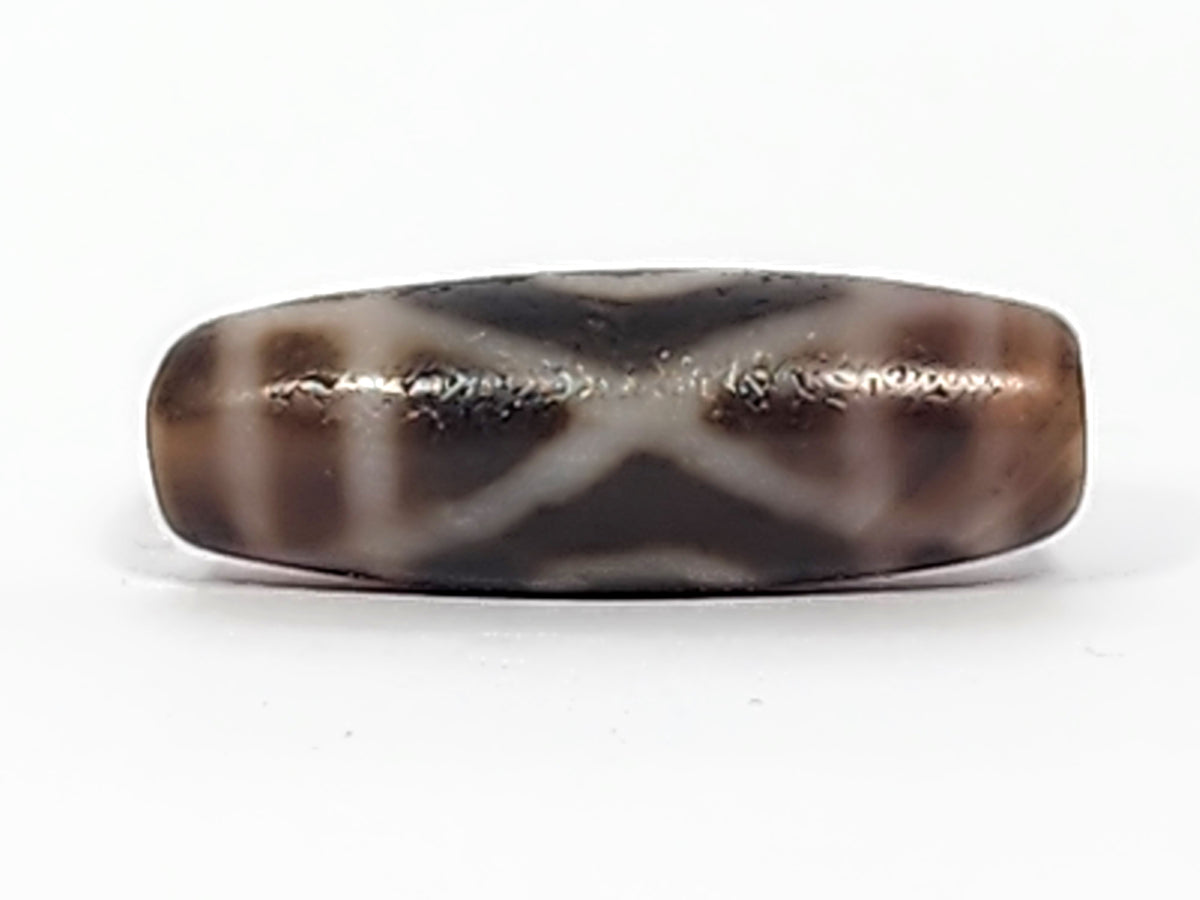 Antique two-eye dzi bead, dark brown agate, white X pattern, visible bloodspots, aged patina, elongated barrel shape