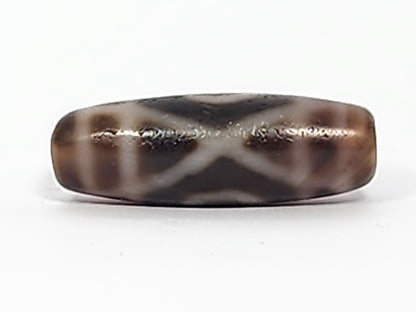 Antique two-eye dzi bead, dark brown agate, white X pattern, visible bloodspots, aged patina, elongated barrel shape