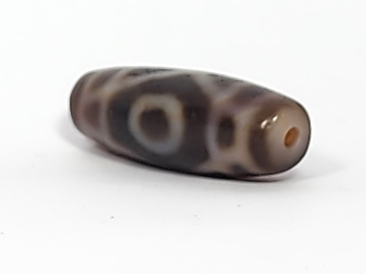 Antique two-eye dzi bead, dark brown agate, cream eye motifs, visible drill hole, bloodspots, aged patina surface