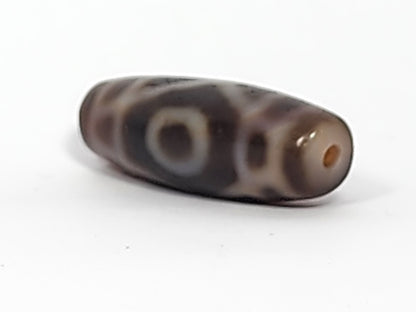 Antique two-eye dzi bead, dark brown agate, cream eye motifs, visible drill hole, bloodspots, aged patina surface