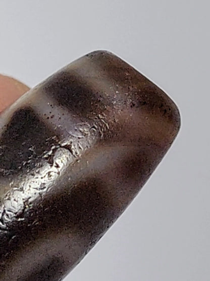Antique two-eye dzi bead agate dark brown patina silver bloodspots worn surface close-up macro detail