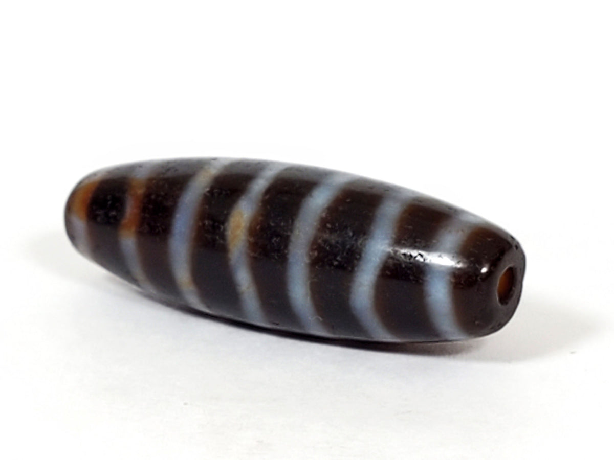 At-053126-WS2, angled end-cap view, drilled hole, stripe bands wrap spindle form, chocolate-brown agate, unretouched