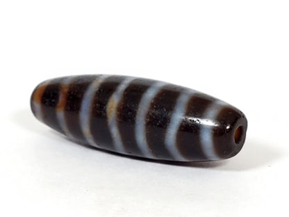At-053126-WS2, angled end-cap view, drilled hole, stripe bands wrap spindle form, chocolate-brown agate, unretouched