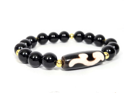 Side angle of vintage dzi bracelet showing the elongated Ruyi bead, cloud-white motif, and mirror-finish black agate beads with gold spacers