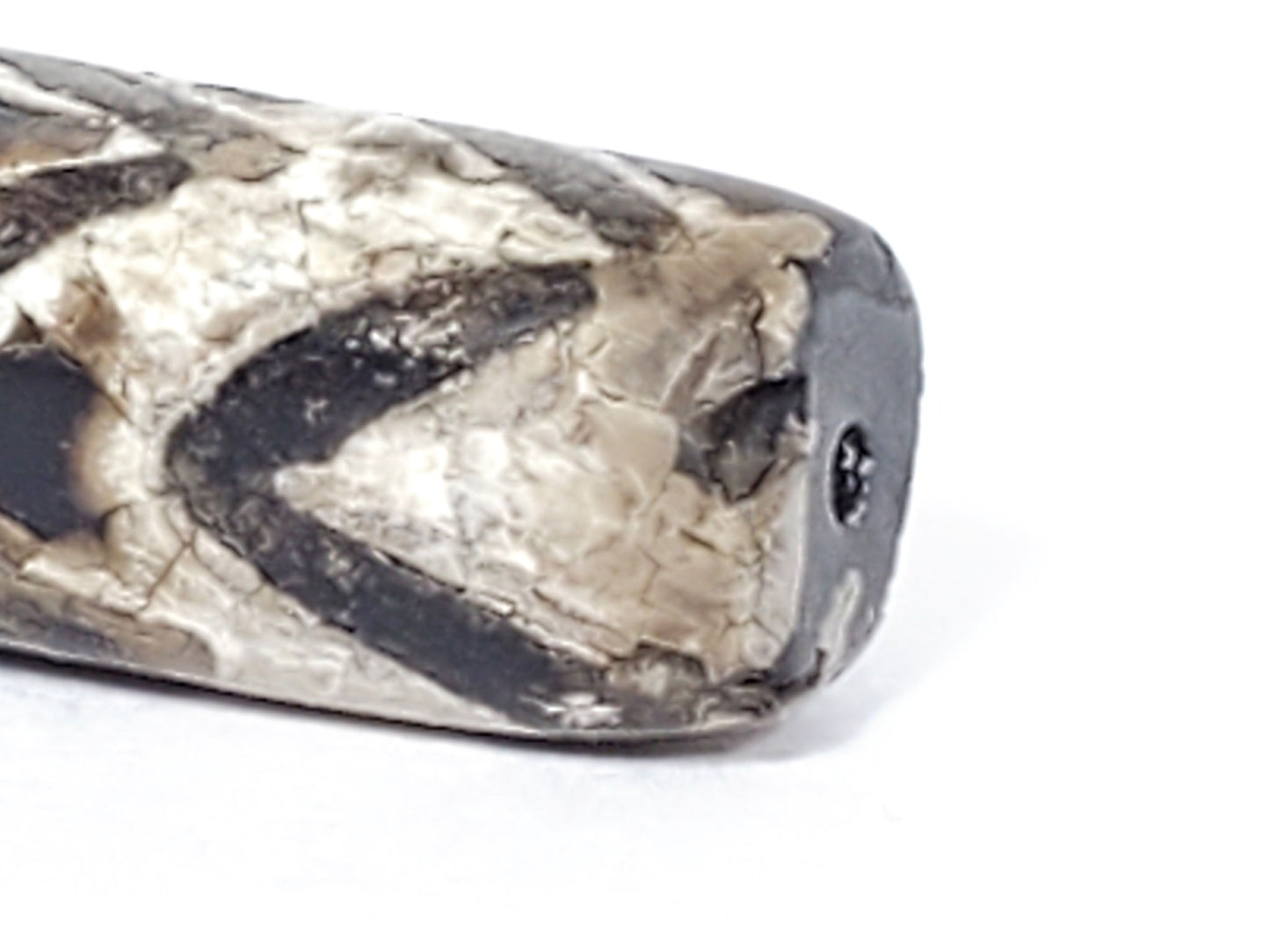 Extreme close-up of drill hole end on ancient Four-Row Tiger Tooth Dzi bead — thick cream-grey calcification encrustation over tiger tooth pattern, 800–1,000 years old
