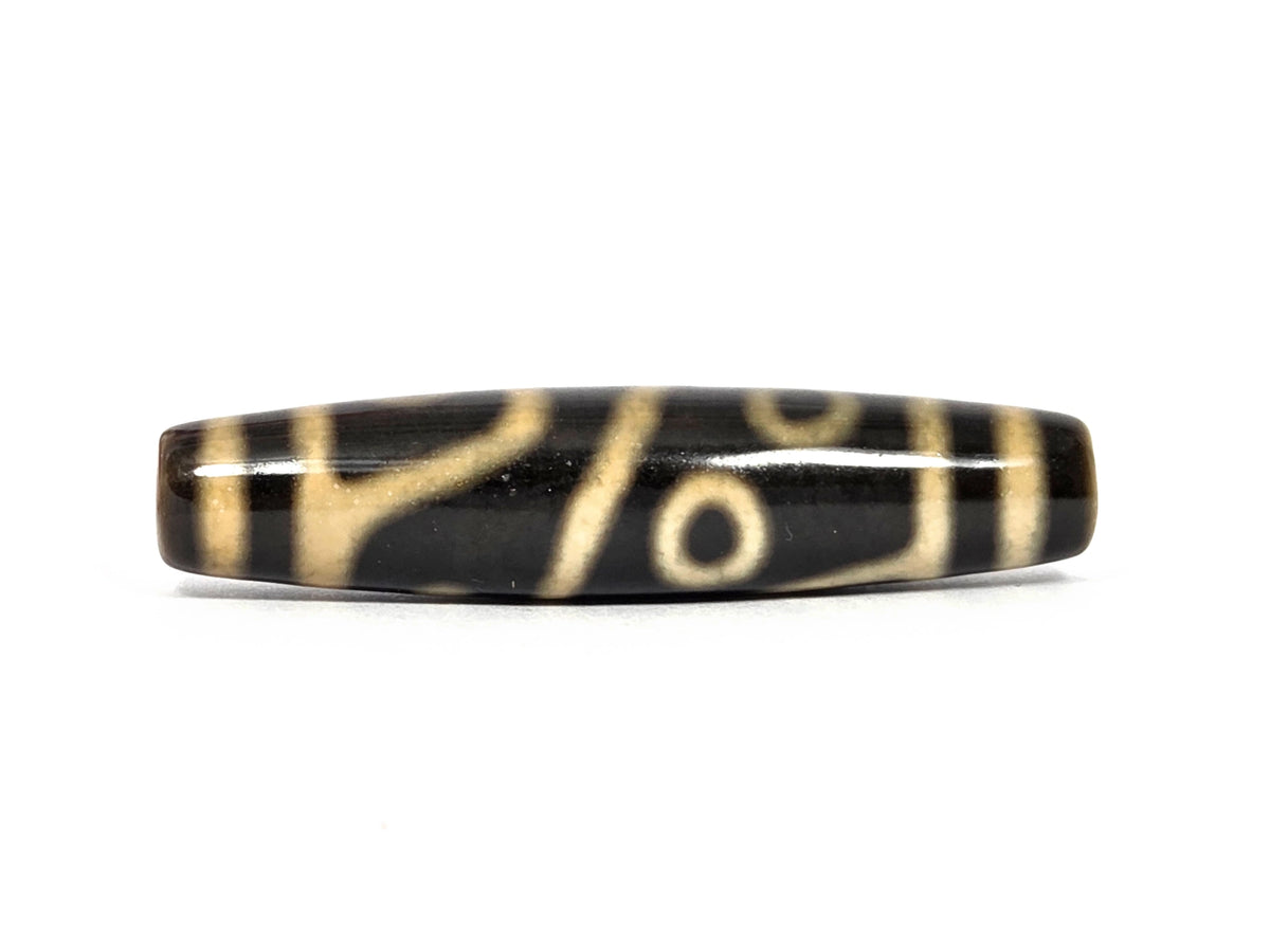 New four eye variant dzi bead N-102526-4EVS showing the star — a small solid cream dot near the left end bands — beside a curved line and a framed cream eye toward the right end, on dark brown agate with a bright polish