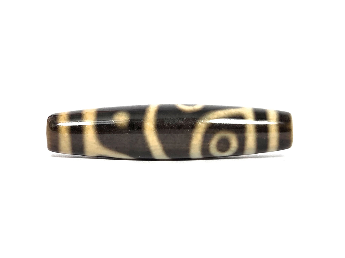 Third face of new four eye variant dzi bead N-102526-4EVS — two cream eyes on opposite edges of the barrel, one low near the left end and one high in a curved frame near the right, separated by a diagonal cream line, dark brown agate, 57.8 mm × 13.2 mm
