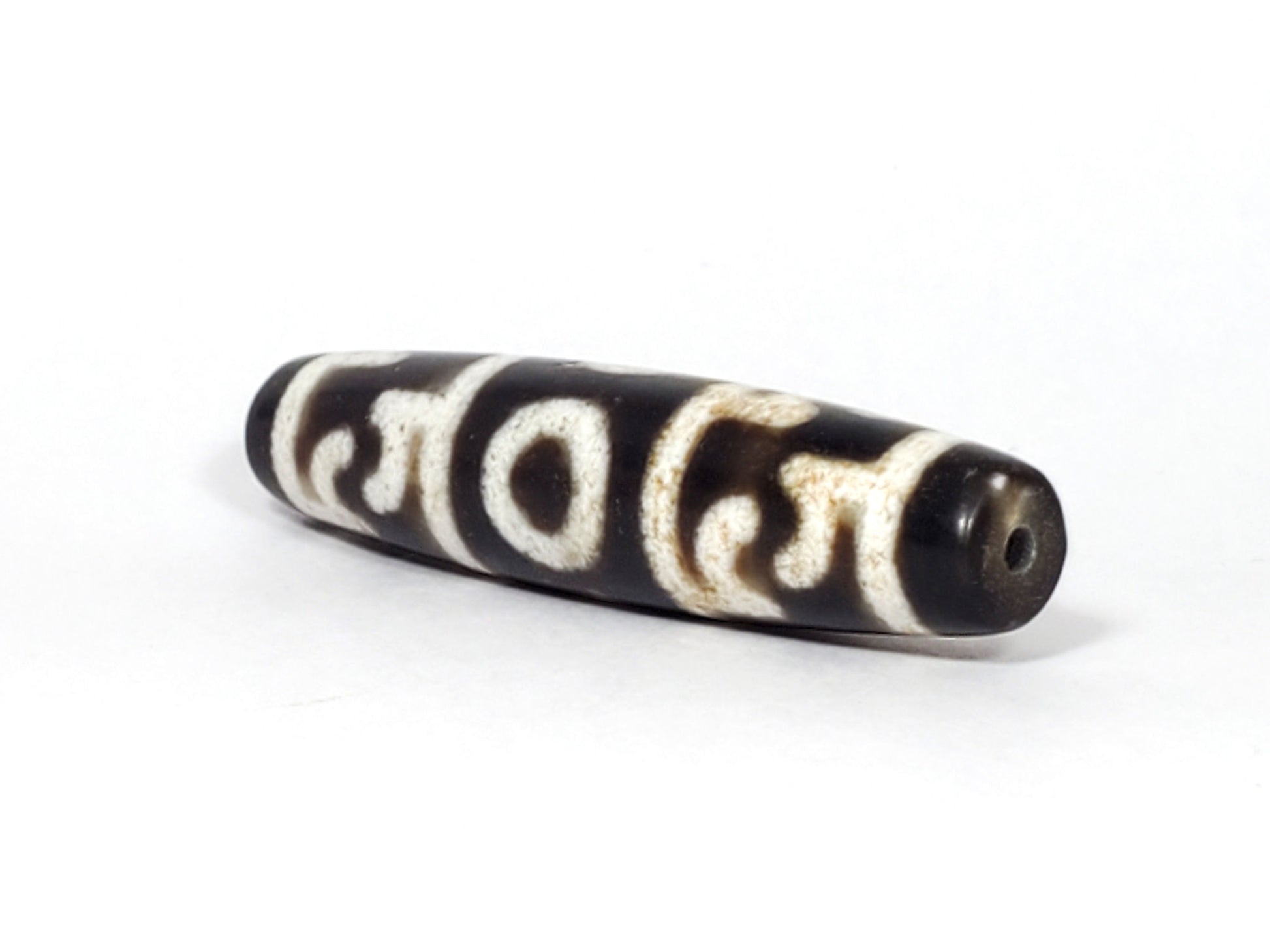 N-062226-GRRP, angled view toward narrow tapered tip, drill hole centred, motif wrapping body, unretouched