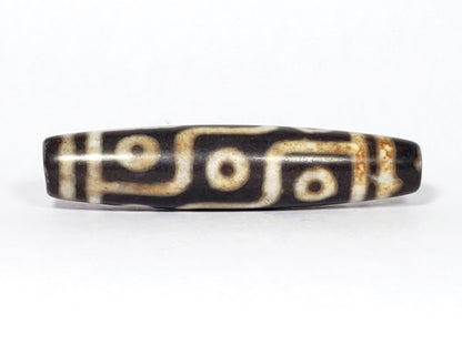N-062226-9E2, face B, nine eye flowing curved-line motif, dark warm brown ground, warm cream-white lines, unretouched