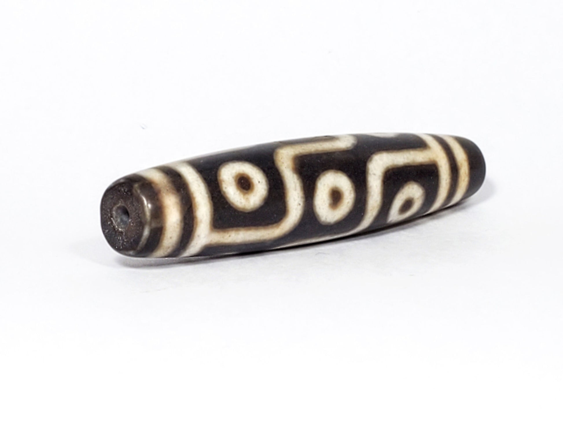 N-062226-9E2, angled view toward broader end, drill hole centred, warm cream motif visible, dark warm brown, unretouched