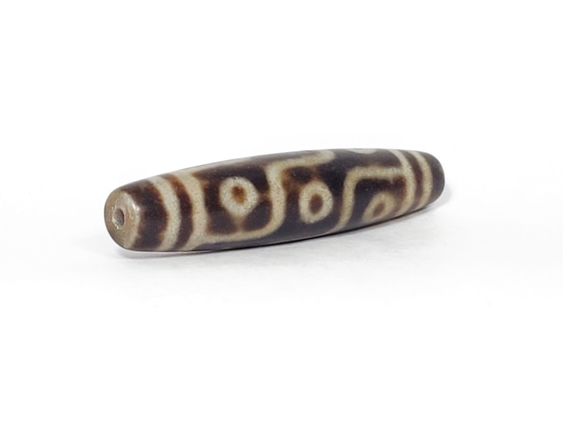 N-062226-9E3, angled view toward other end, drill hole centred, symmetric taper, warm brown matte ground, unretouched