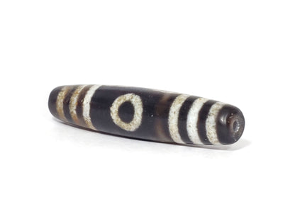 N-062426-3E2 new three eye dzi 57.9x13.3mm angled view narrow pointed end small drill hole near-black tip unretouched