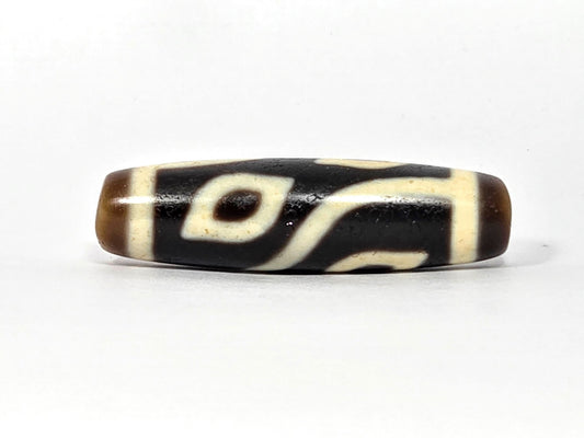 Four-eye dzi bead, dark brown and black agate, cream white eye motifs, wave pattern, polished surface, 40mm elongated barrel shape