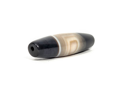N-N-080426-1E5 natural one eye dzi bead 54.4×14.1mm, opposite angled end view showing cream banding meeting pitch-black cap and drill hole, unretouched