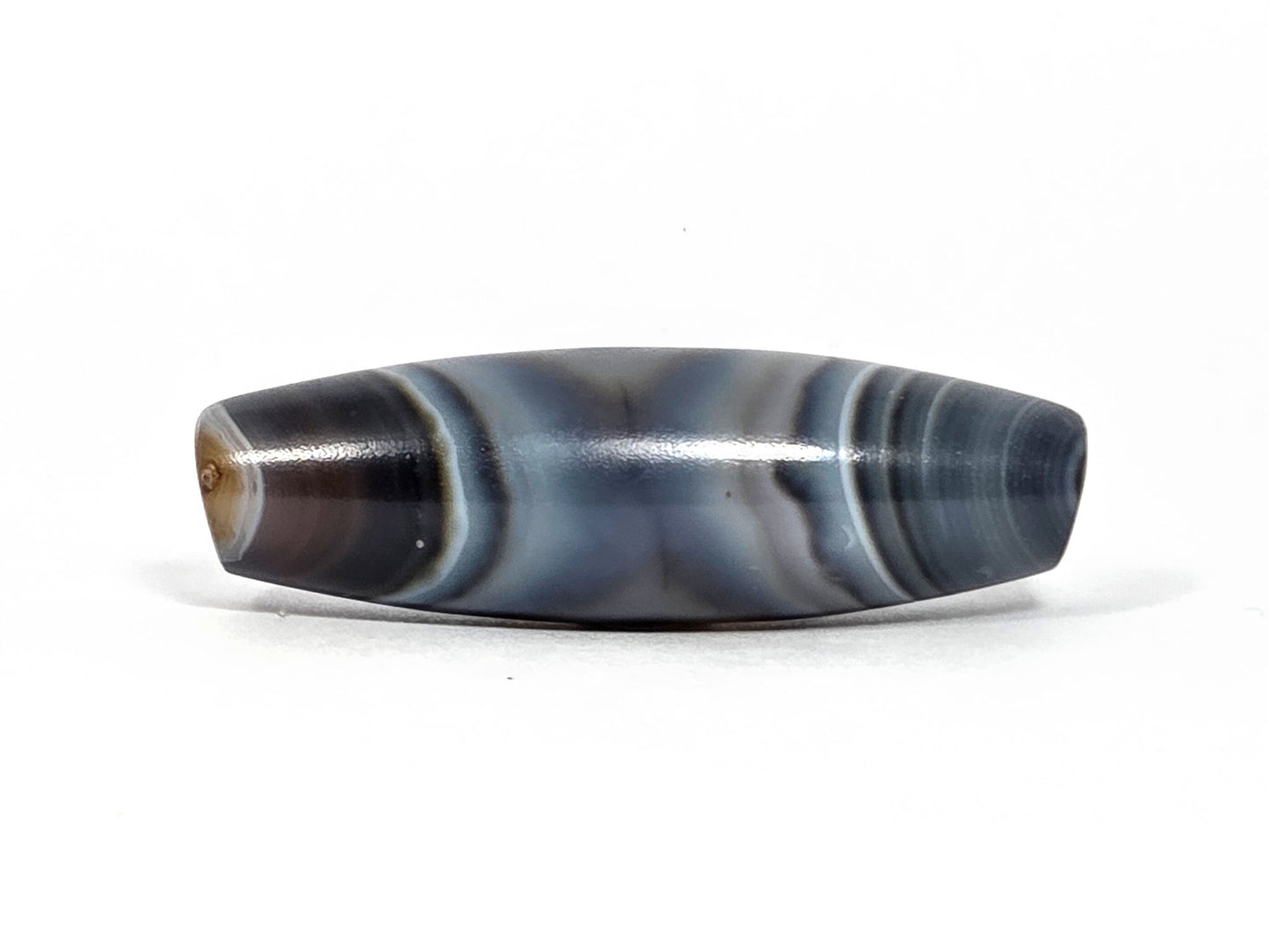 N-N-080926-1E6 natural one eye dzi bead 50.5×15.8mm, turn view showing warm dark brown drill end zone and parallel blue-grey body banding, unretouched