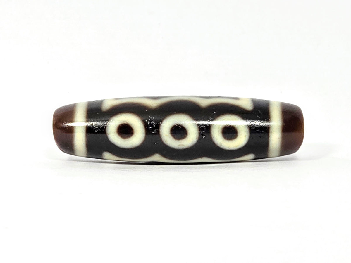 Five-eye dzi bead, dark brown agate, white eye motifs, wave pattern, glossy surface, elongated barrel shape, 41mm