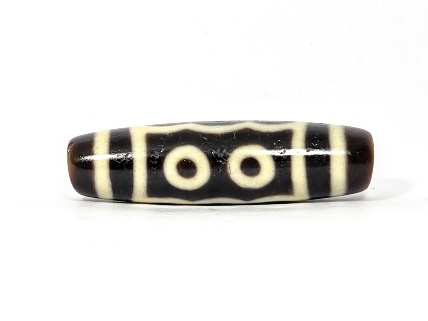 Black and white striped cylindrical bead on a white background