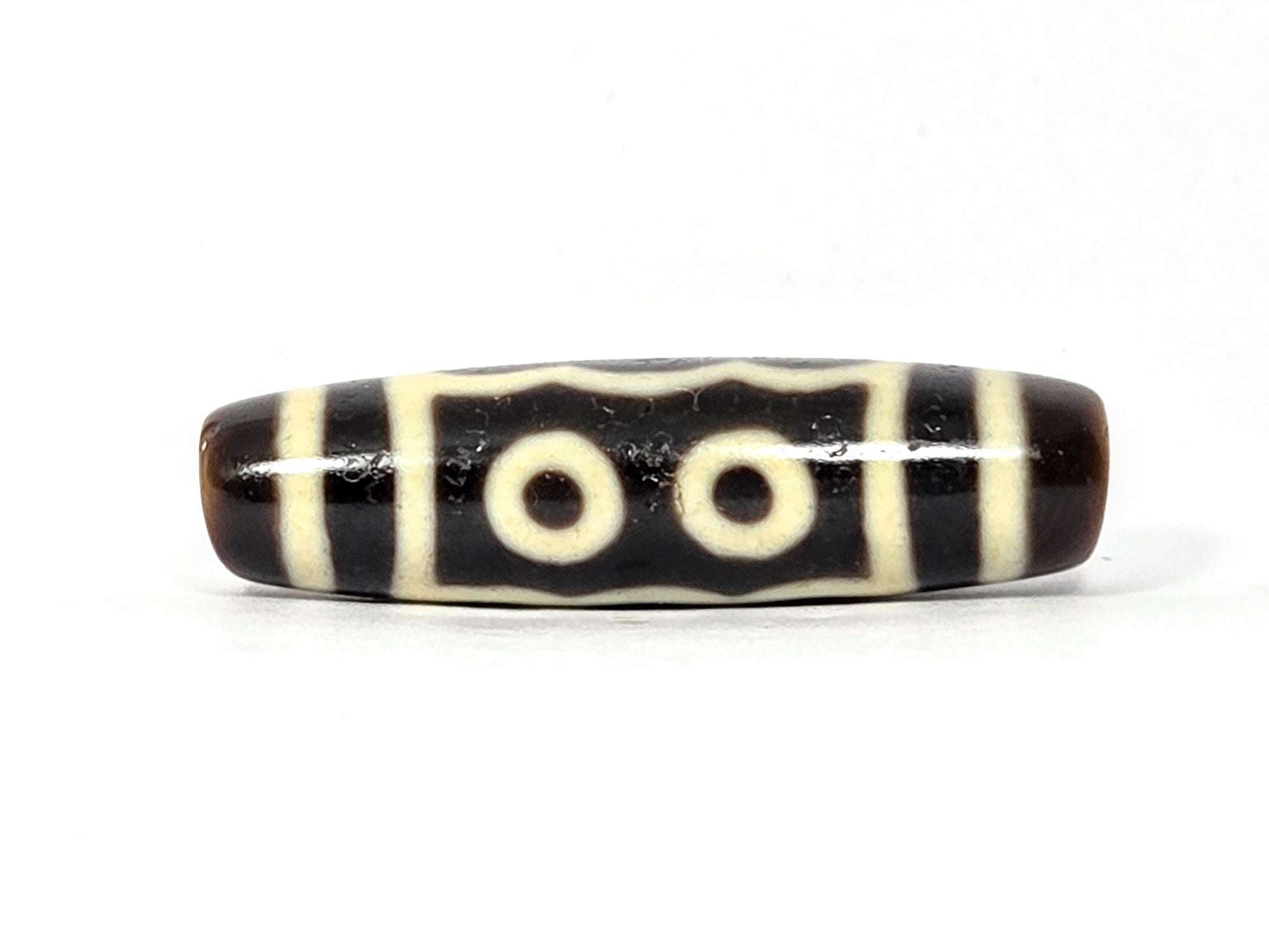 Black and white striped cylindrical bead on a white background