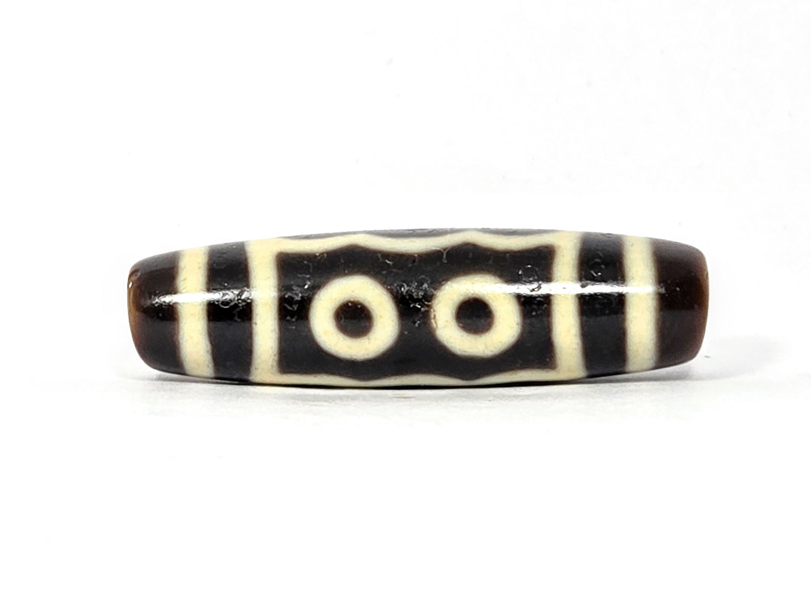 Black and white striped cylindrical bead on a white background