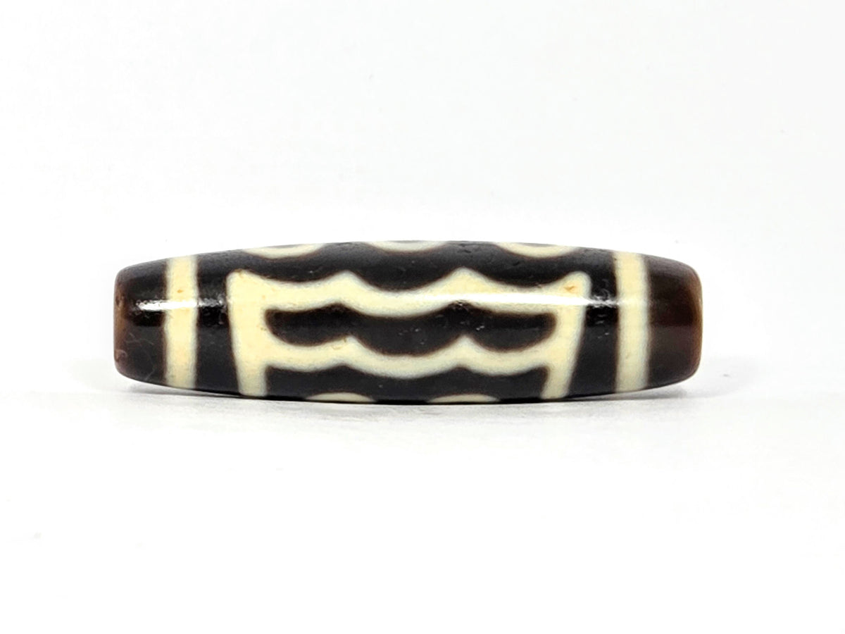 Five-eye dzi bead, dark brown agate, cream wave motifs, visible drill holes, aged patina, 40.5×11.4mm barrel shape