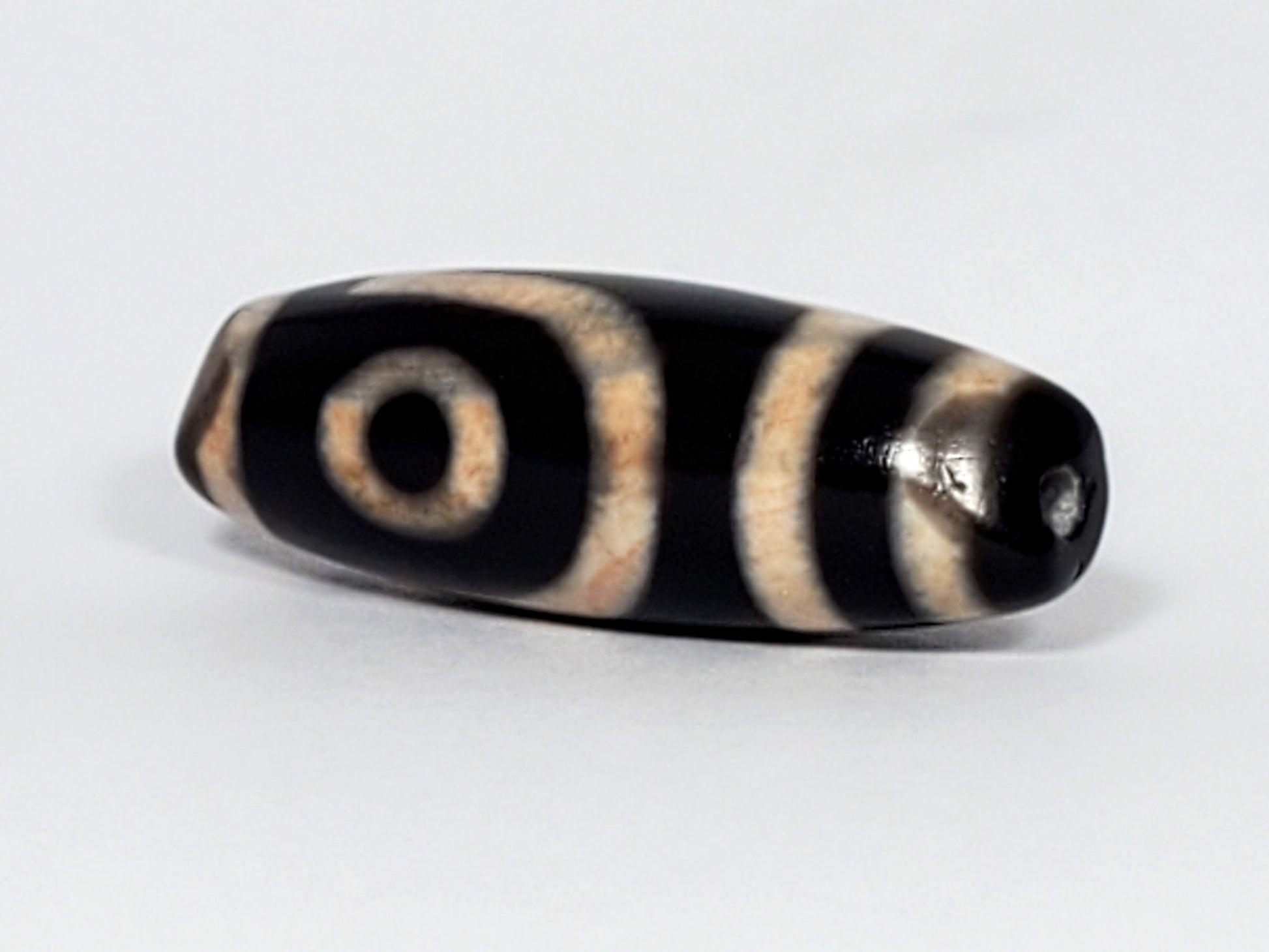 N-062426-2E new two eye dzi 37.7x13.0mm angled view eye face pitch-black tip small drill hole peach-cream unretouched
