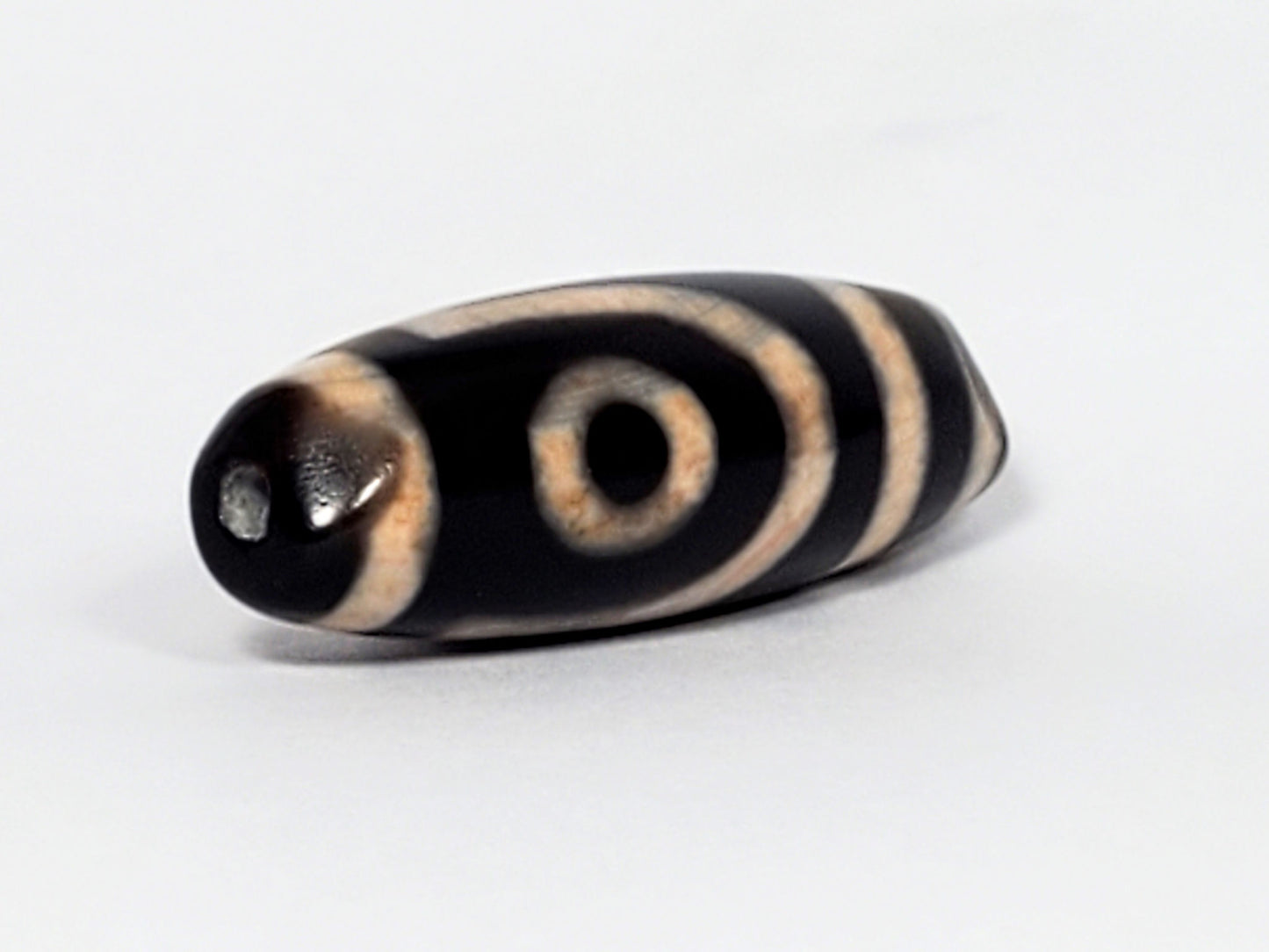 N-062426-2E new two eye dzi 37.7x13.0mm angled view opposite end pitch-black tip drill hole warm peach motif unretouched