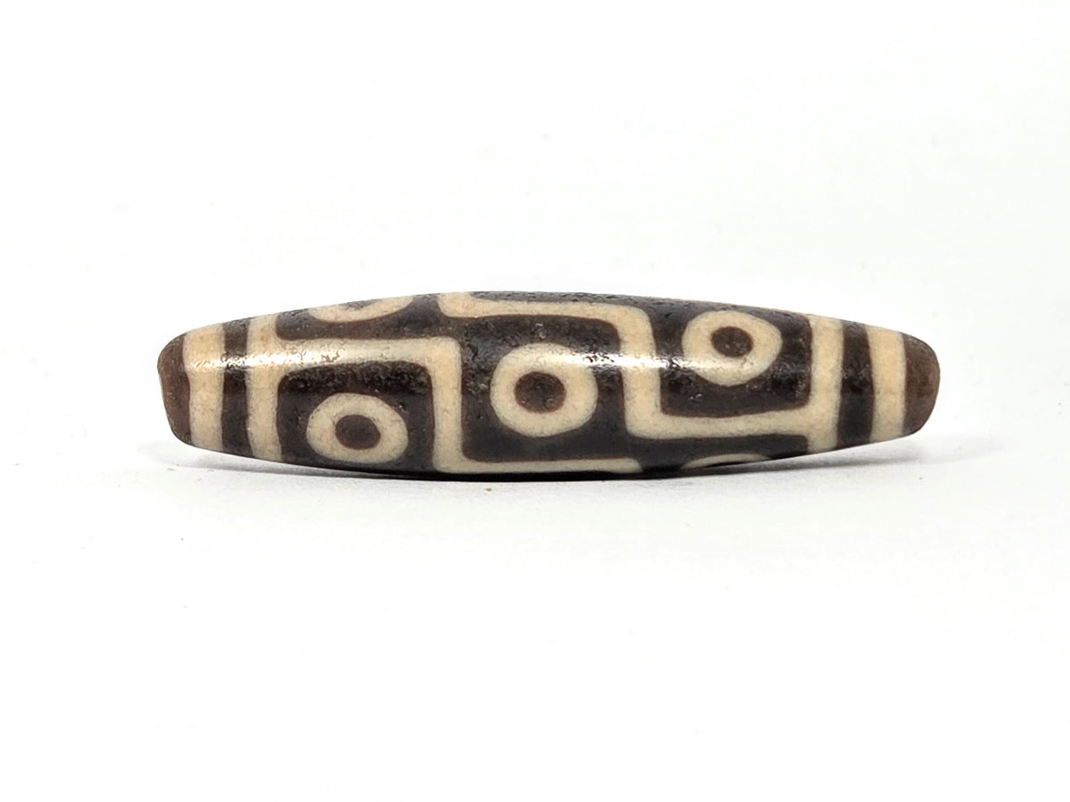 Tibetan dzi bead with four-eye motif, cream and dark brown agate striping, polished surface, drilled holes