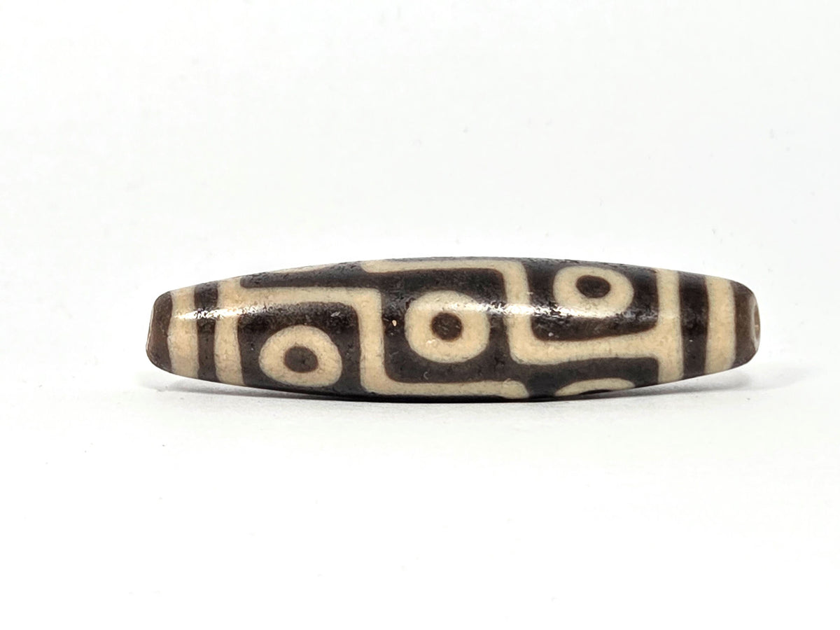 Tibetan dzi agate bead with nine-eye motif, cream and dark brown striped pattern, polished surface, drilled focal bead