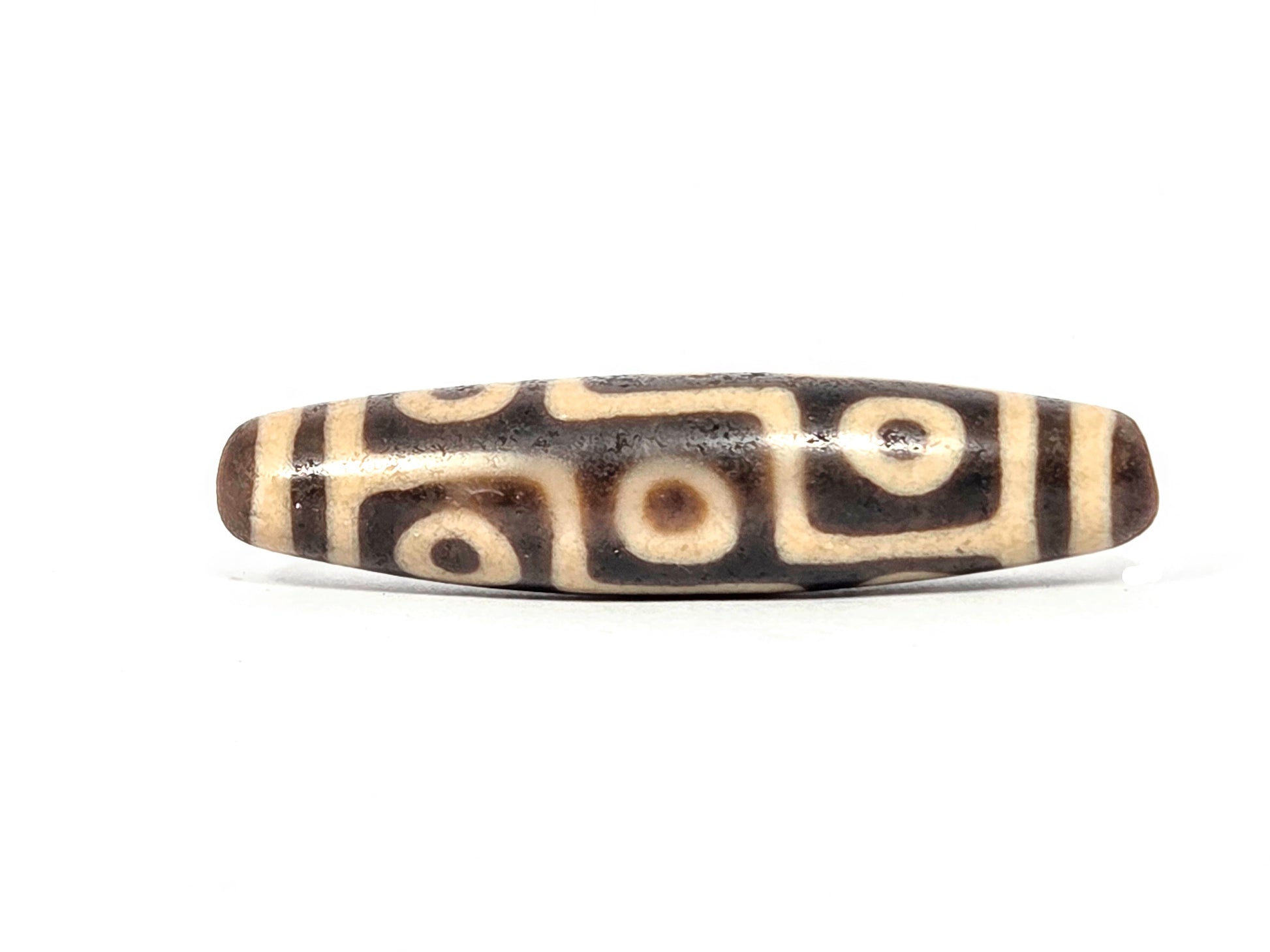 Close-up of nine eye motif on ancient Tibetan dzi bead — crisp eye pattern on natural agate, over 1000 years old