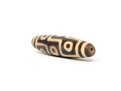 Ac-032326-9E5 left drill hole end, sandy-tan tip, age-granular cream-white surface texture visible, unretouched