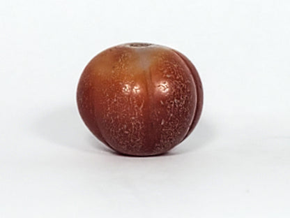 Ac-061126-PKP Bead B third face, honey-gold to warm brown banding, ribbed lobed form, drill hole visible, unretouched