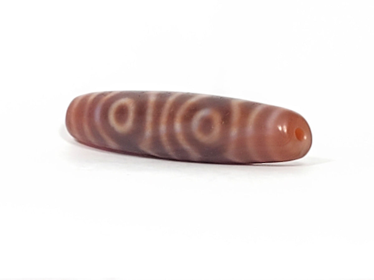 Antique six-eye dzi bead, brown agate, circle motifs, striped patina, visible drill hole, bloodspot, elongated barrel shape