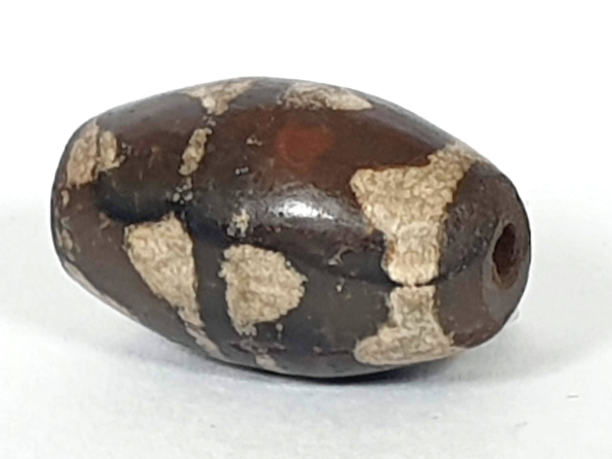 Antique double wave dzi — angled end, drill hole at dark rounded tip, wave motif on compact near-spherical body, At-0426-DW2