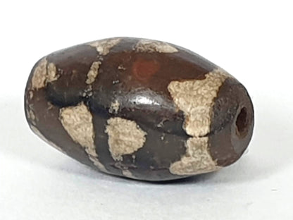Antique double wave dzi — angled end, drill hole at dark rounded tip, wave motif on compact near-spherical body, At-0426-DW2
