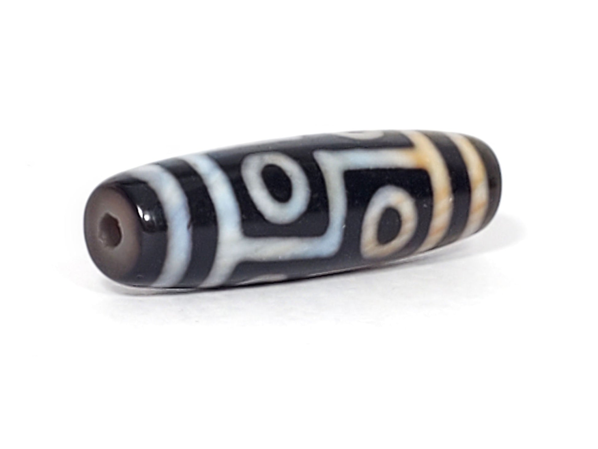 N-051423-6E dzi bead, full diagonal view, cream stepped motif on black, unretouched.