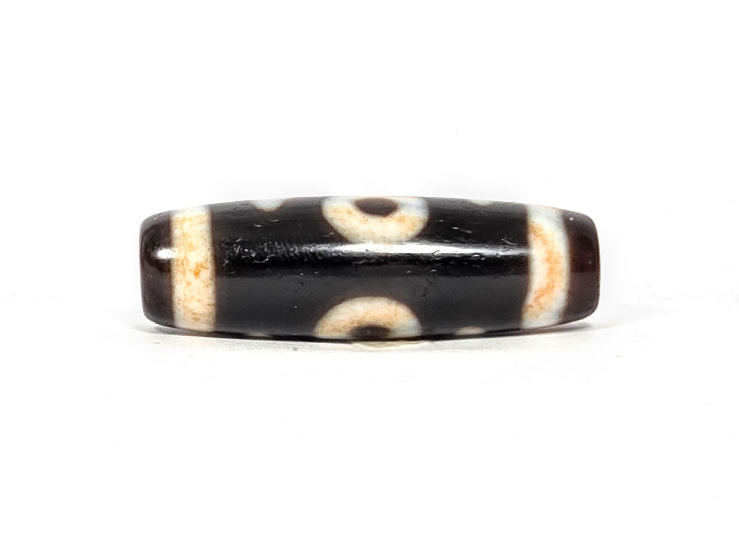 V-021326-BenBS Benefactor dzi bead, fourth face, cream-dark composition, pitch-black and dark brown zones, unretouched.