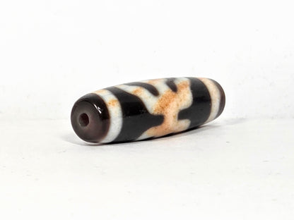 V-021326-BenBS vintage Benefactor dzi bead, second angled end shot, drill hole visible, dark brown end cap, unretouched.