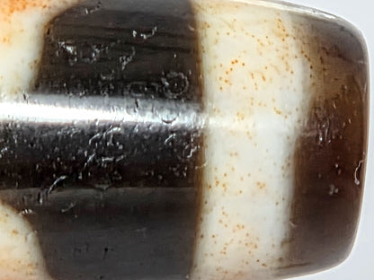 V-021326-BenBS Benefactor dzi bead, macro end cap zone, reddish-orange cinnabar in cream band, unretouched.