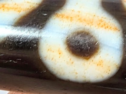 V-021326-BenBS Benefactor dzi bead, macro eye-ring zone, pervasive russet cinnabar throughout cream ring, unretouched.