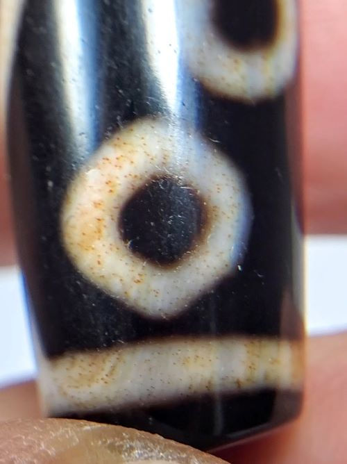 V-102723-6EBS Six Eye dzi bead, macro close-up of single eye ring, bloodspot micro-dots visible, unretouched