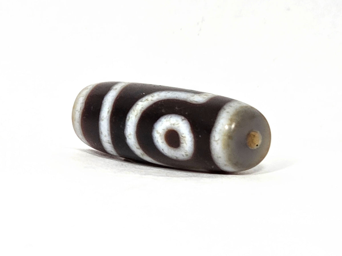 V-062126-2E dzi bead, opposite angled view showing end cap and drill hole, unretouched