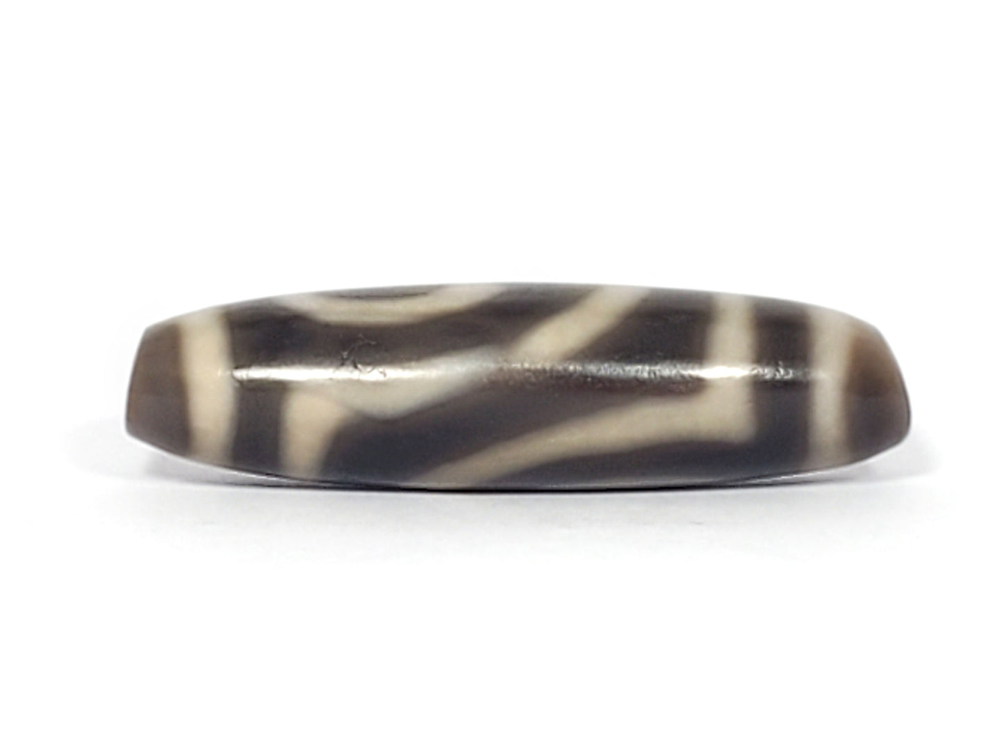 Second face of ancient Two Eye Dzi — sweeping cream pattern on deep grey-brown agate