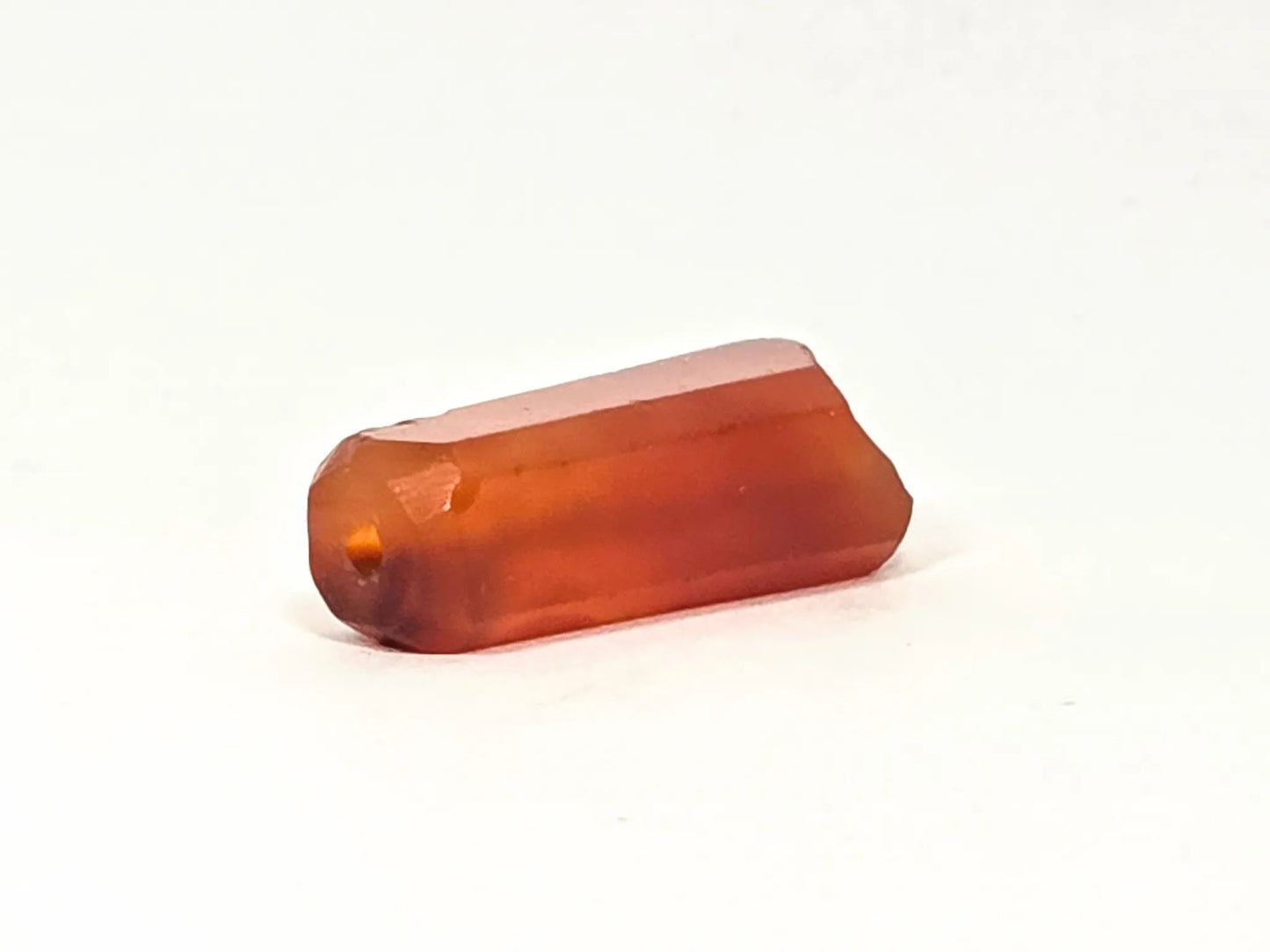 Chipped end of ancient beveled carnelian bead — drill hole visible as worn orange circle, ancient chipping around end face, 500–1,000 years old, genuine Indus Valley bead