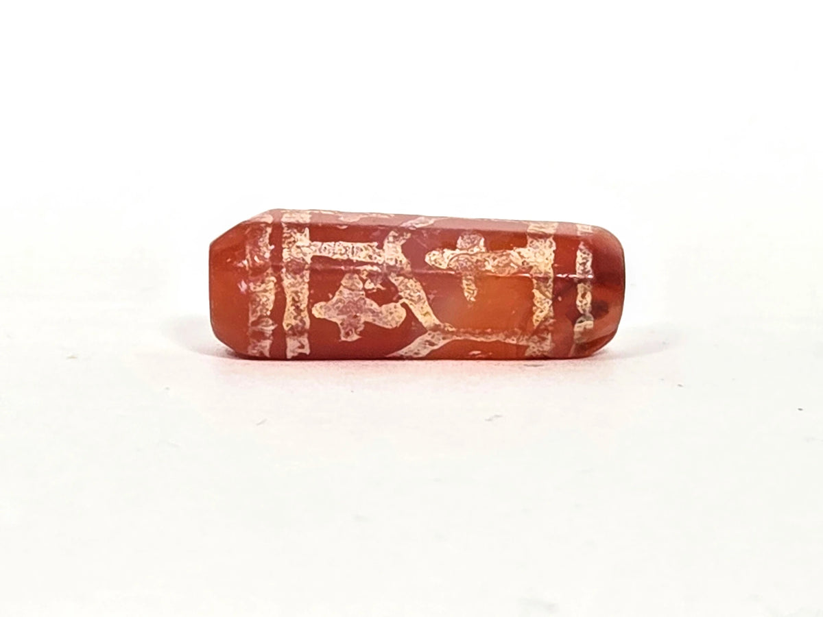 Second lateral profile of ancient etched carnelian cross and longevity motif bead showing framed panel compositions with abstract cross and character forms in thick mineralised white etching on warm red carnelian, 27 mm