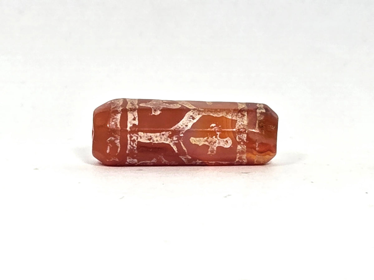 Third lateral profile of ancient carnelian cross and longevity bead (AC-101026-CL6) showing further faces of the tapered octagonal form with cream-white alkaline etching on saturated brick-red carnelian, 27 mm