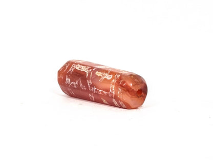 Angled end view of ancient etched carnelian bead showing small drill hole at the wider end, full octagonal faceting visible, deep translucent red-orange carnelian, 500–1000 years old