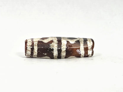 Second lateral profile of ancient etched carnelian bead showing reverse face with grid and band motif etching on warm amber-brown carnelian, octagonal faceted body with crystalline white etched surface, 31.1 mm × 10.4 mm