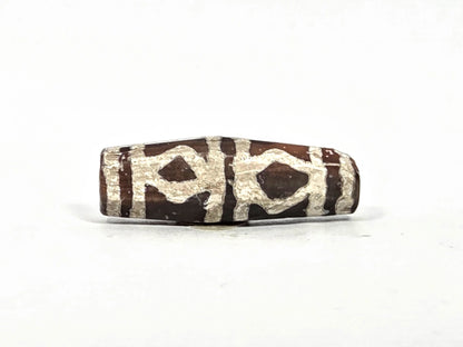Third lateral profile of ancient etched carnelian bead AC-101226-EC showing diamond lozenge motif units with vertical band separators on eight-sided faceted barrel, warm reddish-brown carnelian ground, 700–1000 years old