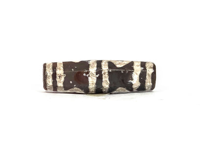 Fourth lateral profile of ancient etched carnelian bead showing horizontal band-dominant face with partial geometric motif elements, silver-white etching on deep amber-brown carnelian, octagonal faceted form